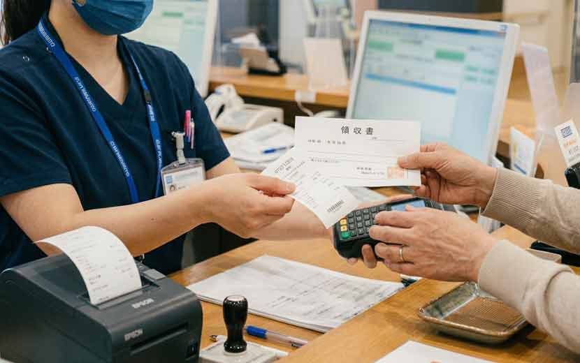 カード決済の控えと領収書を受け取る患者の手元イメージ