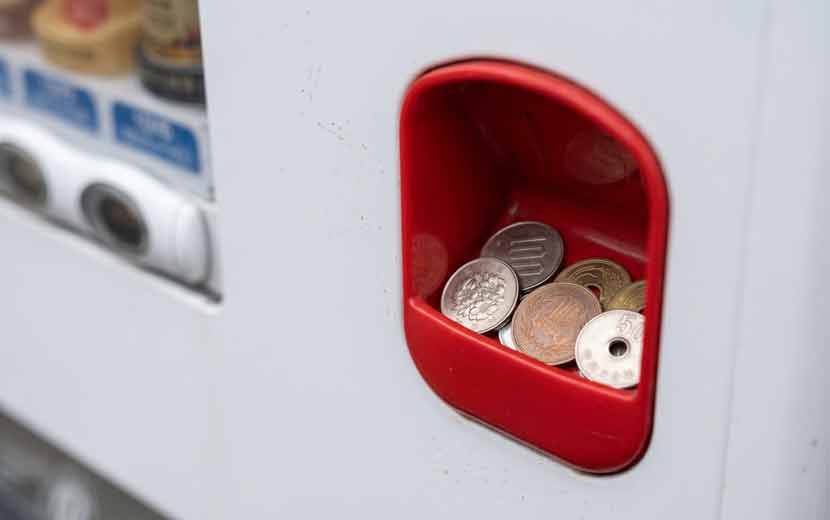 自動販売機の釣銭返却口とコインのイメージ